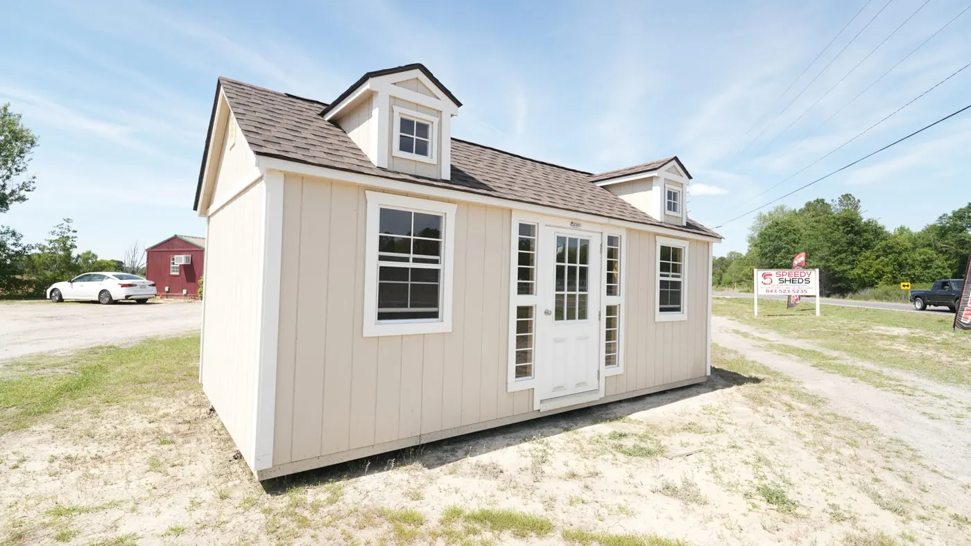 Cottage shed with a roof dormer, cottage trim and a color-matched body on a gravel pad